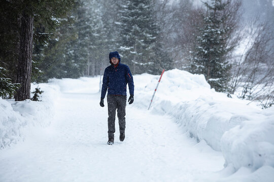 Man Walking Along a Snow-Covered Mountain Trail