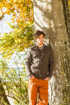 Young Man Leaning Against a Tree Surrounded by Vibrant Autumn Colors.