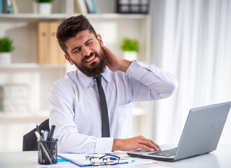 Obraz premium Businessman with neck pain at laptop.