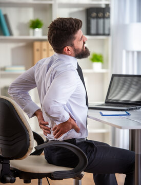 Businessman with lower back pain sitting.