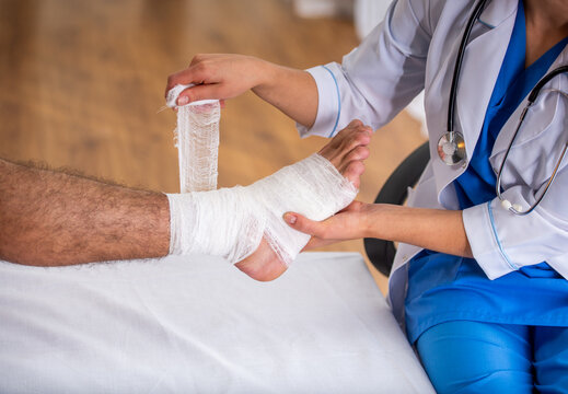 Doctor bandaging injured ankle.