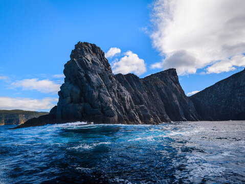 Cape Raoul seascape with rock platforms, towering cliffs, columns, blue sky, and the Tasman Sea in Tasmania, Australia