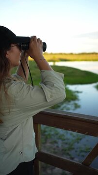 Young ornithologist birdwatching with binoculars in nature reserve