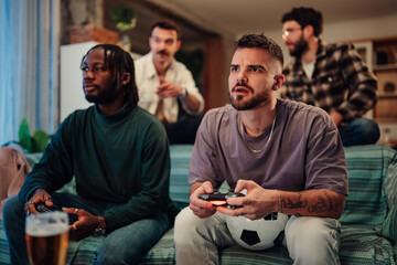 Diverse friends enjoying intense online soccer game at home, bonding over competitive multiplayer video gaming session © Zamrznuti tonovi