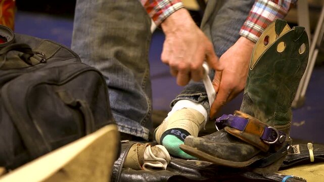 Close up of bull rider taping up boots and pants