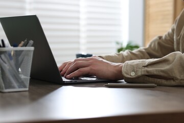 Fototapeta premium Man working on laptop at wooden desk in office, closeup