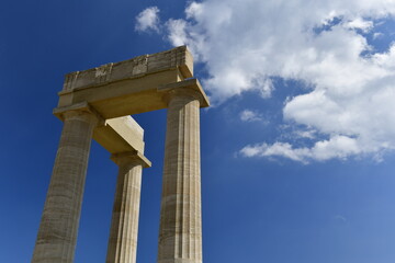 Lindos Acropolis, Lindos, Rhodes Island, Greece. The tall column and cornice of an archeological Roman-Greek temple site of Athena from the 4th century BC in Spring. © alagz