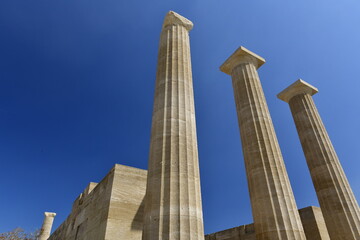 Lindos Acropolis, Lindos, Rhodes Island, Greece. The tall column and cornice of an archeological Roman-Greek temple site of Athena from the 4th century BC in Spring. © alagz