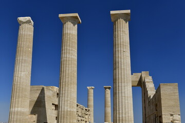 Lindos Acropolis, Lindos, Rhodes Island, Greece. The tall column and cornice of an archeological Roman-Greek temple site of Athena from the 4th century BC in Spring. © alagz
