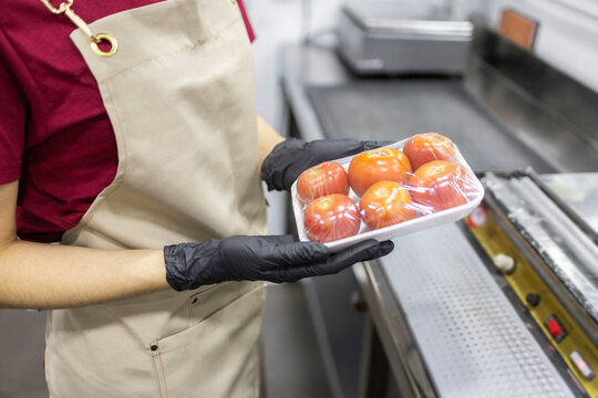 Shop assistant preparing packaged tomatoes for sale
