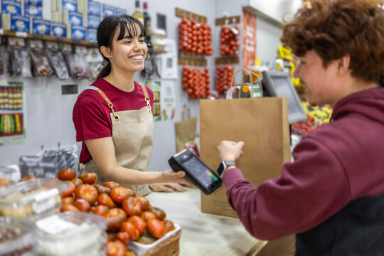 Shop assistant smiling at checkout counter in fruit store