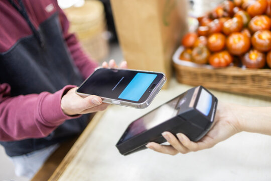 Customer using mobile payment at fruit store checkout