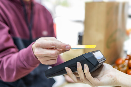 Shop assistant processing payment at fruit store counter