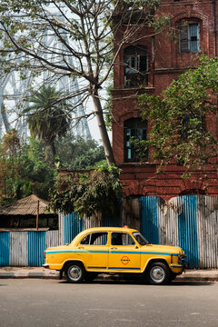 Iconic yellow taxi beside a vintage building in India