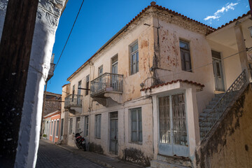 Obraz premium Street lined with traditional stone houses in Leonidio, Greece, captured on a sunny day. Authentic Mediterranean village architecture with warm light, historic character, and peaceful atmosphere.