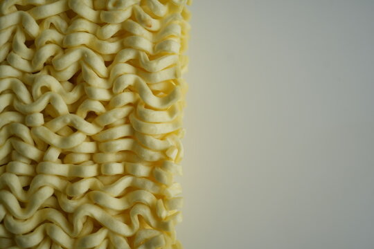 macro texture of instant noodles with repeating wavy pattern. Close-up of dry ramen showing detailed structure and soft beige tones. Organic abstract background perfect for food concepts, packaging de