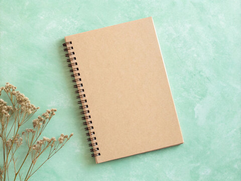 Kraft Spiral Notebook with Dried Wildflowers Flat Lay on Mint Green Background