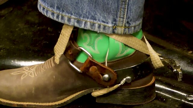Close up of cowboy strapping up leather boots 
