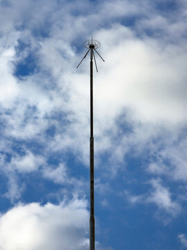 Tall lightning rod reaching blue sky with clouds