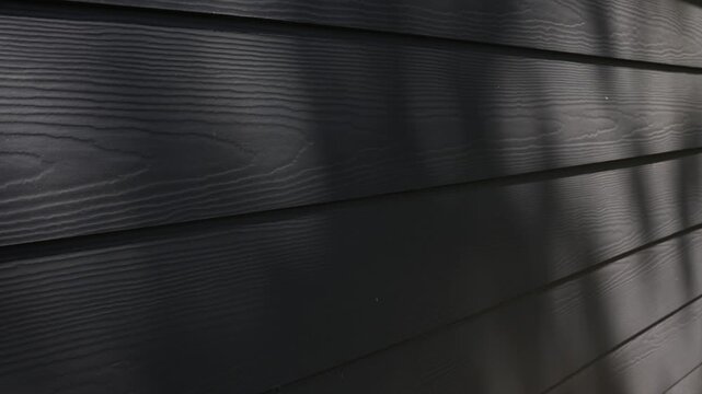 4k video angled view of home exterior with moving tree shadows on dark gray house siding