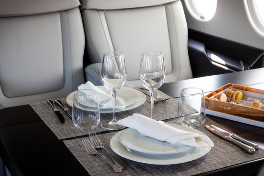 A table set for in-flight dining inside a modern executive business jet, highlighting a luxurious private aviation cabin interior.