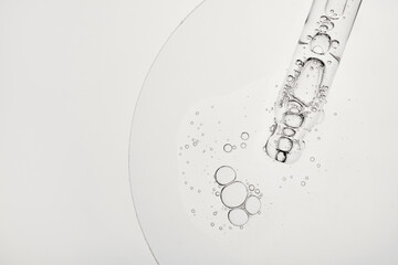 Dropper releasing clear liquid with bubbles, highlighting serum texture and purity