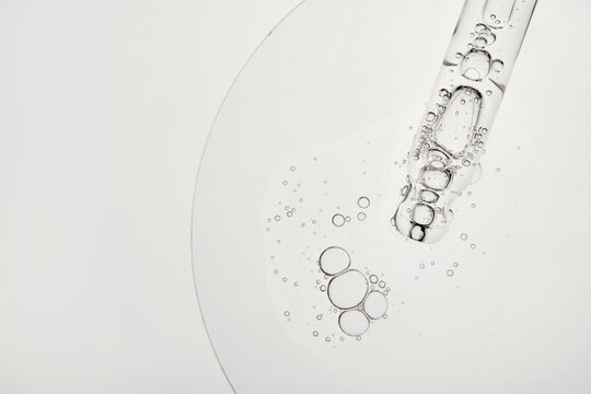 Dropper releasing clear liquid with bubbles, highlighting serum texture and purity