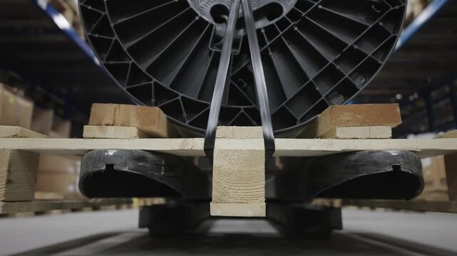 Forklift transport industrial cable spool secured on wooden pallet in production plant warehouse