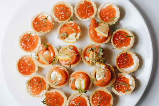 Elegant plate of gourmet canapes topped with red caviar and herbs, perfect for catering events and celebrations.
