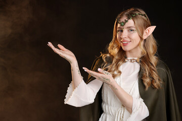 Obraz premium Beautiful elf girl on black background with smoke, space for text