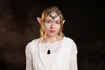 Obraz premium Beautiful girl dressed as elf on black background with smoke