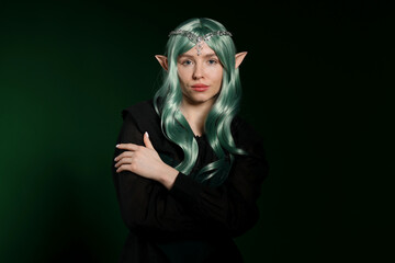 Obraz premium Beautiful girl dressed as elf on dark green background
