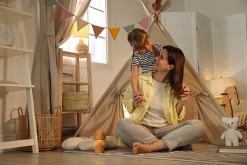 Mother and her daughter near toy wigwam at home © New Africa