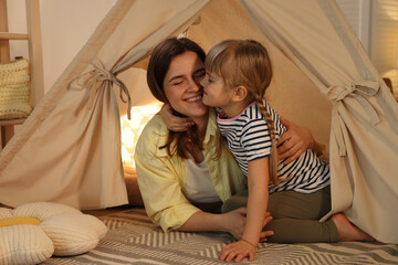 Mother and her daughter in toy wigwam at home © New Africa