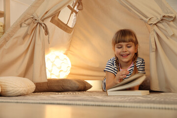 Little girl with book in wigwam at home © New Africa