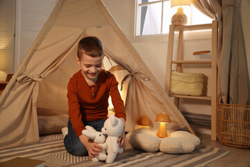 Little boy playing with toys near wigwam at home © New Africa