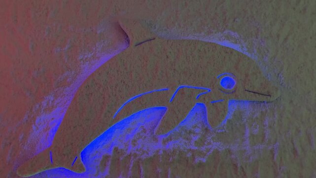 Blue lit dolphin salt relief on textured cave wall, carved sea mammal motif inside therapeutic salt chamber, cool purple and blue.
