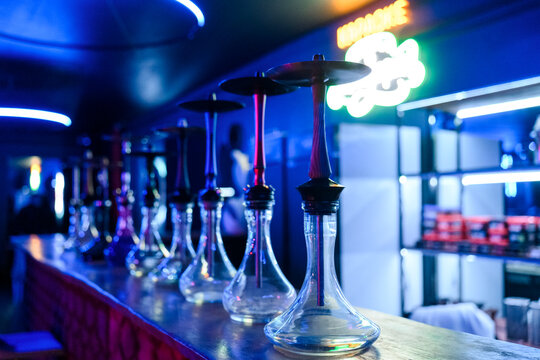 Hookah pipes displayed on bar counter in modern lounge with neon lights