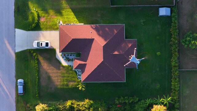 Professional drone pilot capturing aerial photography of suburban housing district. Real estate inspection concept.