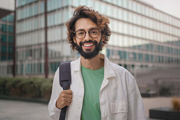 Portrait of young confident man with eyeglasses and beard smiling in the city