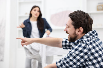Fototapeta premium Gender inequality concept. Man watching movie while his wife ironing clothes indoors, selective focus