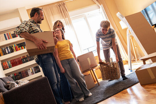 A mother and her kids are unpacking boxes and moving into their new home. They work together to organize their belongings and make the space feel like home.