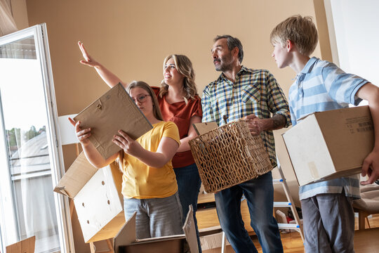 A mother and her kids are unpacking boxes and moving into their new home. They work together to organize their belongings and make the space feel like home.