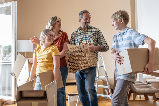 A mother and her kids are unpacking boxes and moving into their new home. They work together to organize their belongings and make the space feel like home.
