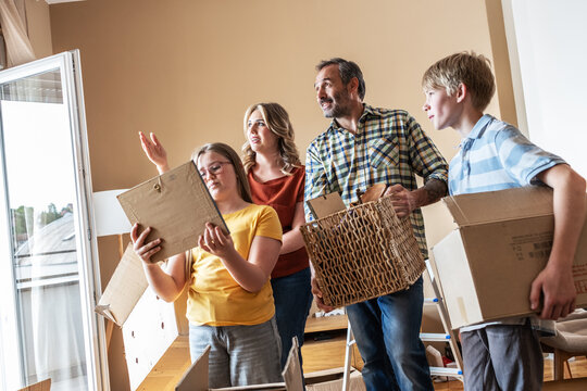 A mother and her kids are unpacking boxes and moving into their new home. They work together to organize their belongings and make the space feel like home.