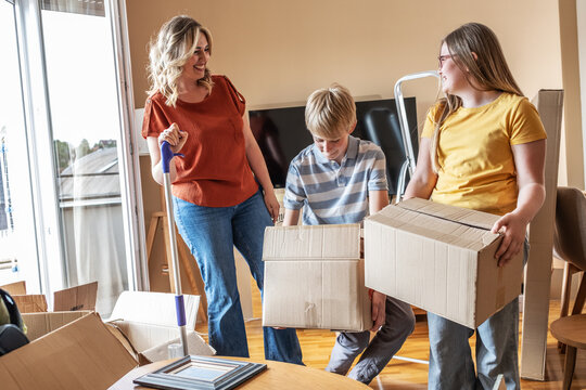 A mother and her kids are unpacking boxes and moving into their new home.