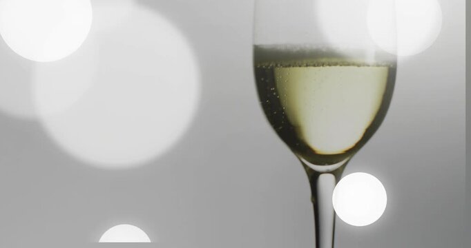 Bokeh discs appearing from left drifting across frame while flute holding bubbles, showing product