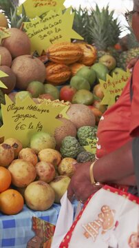 Cinematic Slow Motion Vertical Shot of Tropical Fruit Stall: Customer Reaching for Cacao Pods at Martinique Market