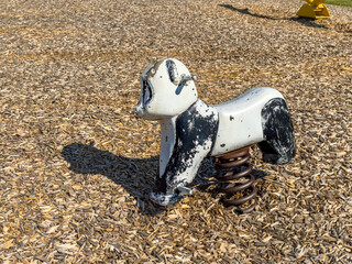 Old metal rocking panda, animal form, riding playground equipment for young children at a park, school, with chipped white and black paint. 