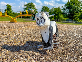 Old metal rocking panda, animal form, riding playground equipment for young children at a park, school, with chipped white and black paint. 